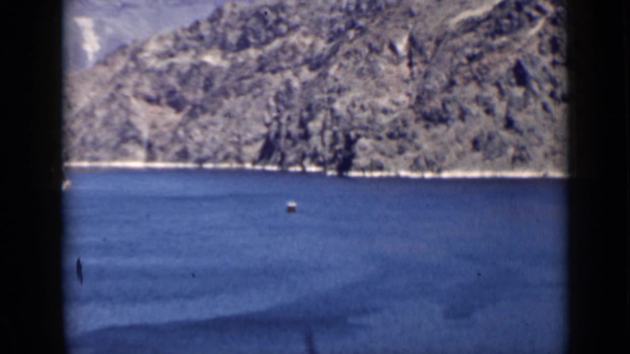 Lake and mountain view with a small buoy near the center of the water.