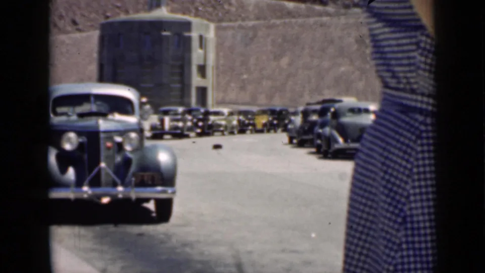1939 Arizona roadside scene with parked automobiles and a woman in a striped dress partly entering the frame.