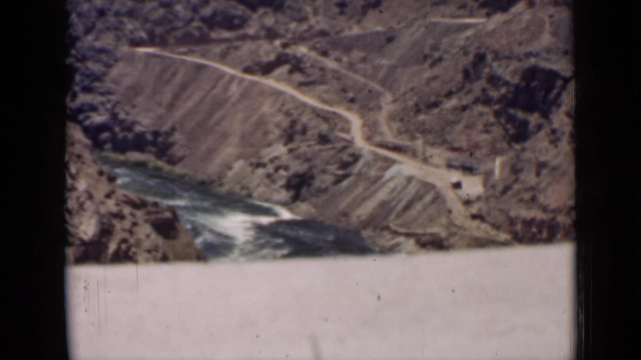 High canyon view with road, river, and pale dam surface in the foreground.