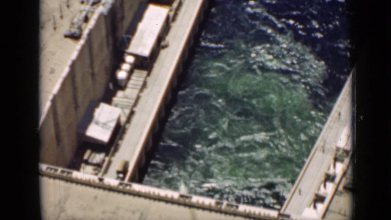 High-angle view of turbulent green water inside a concrete canal structure.