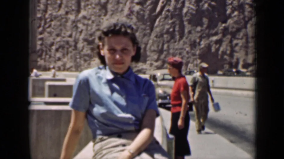 Arizona 1939 home-movie frame showing the seated woman at the roadside with a woman in red, a uniformed-looking man and a car in back.