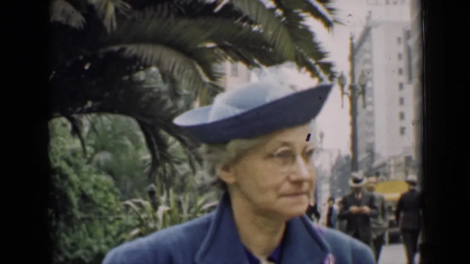 Older woman wearing a blue hat and coat appears on a city sidewalk, likely from the same 1939 home-movie reel.