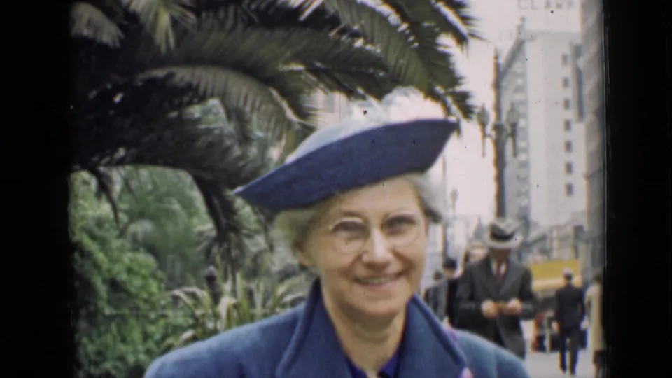The woman smiles toward the camera in the 1939 Arizona park scene, with palm foliage and passersby behind her.