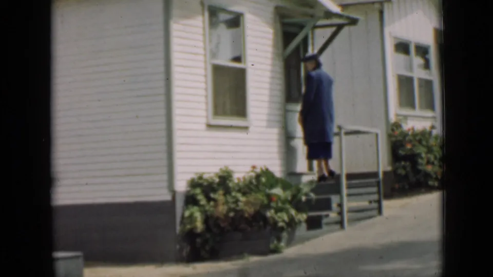 The woman reaches the top of the steps near the doorway of a white clapboard house in the 1939 Arizona home movie.