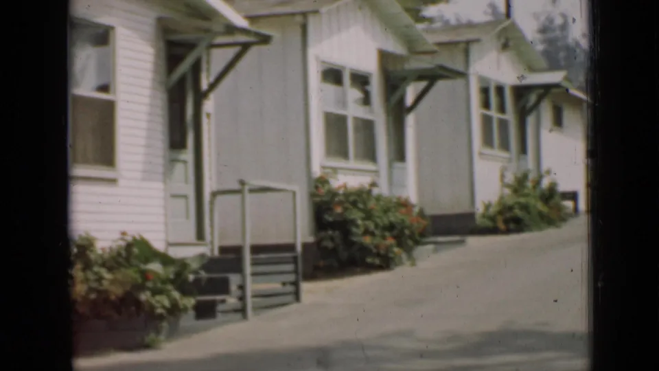 1939 Arizona residential view showing similar white-sided houses with green trim, porch entries, paved drive, and flowerbeds.