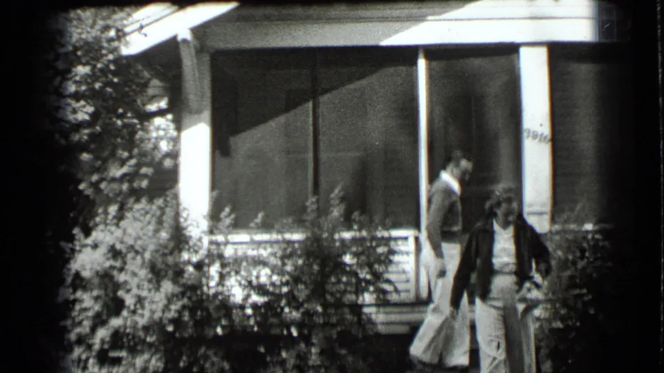 The couple descends from the porch of the Clear Lake residence, framed by shrubs and the screened front entry.