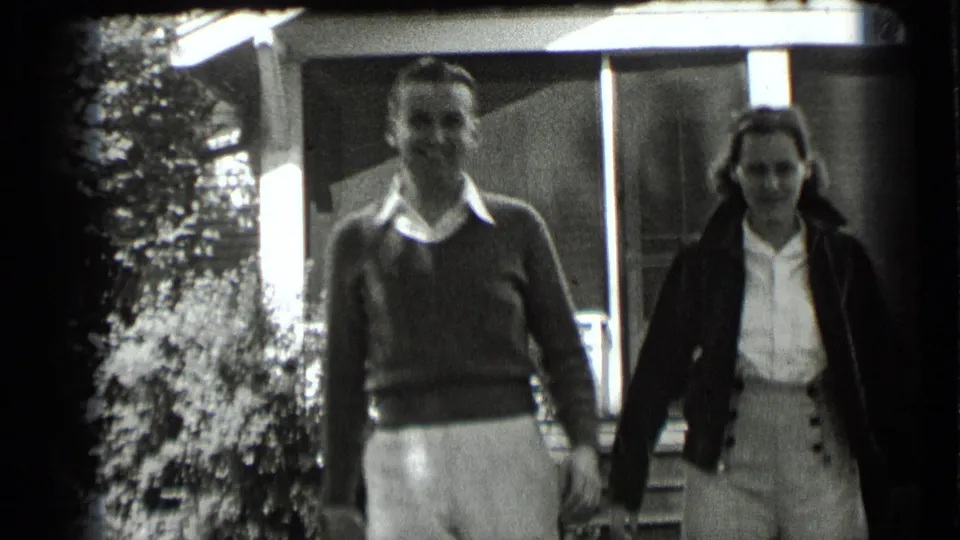 The man and woman approach the camera from a house exterior in 1939 Clear Lake footage.