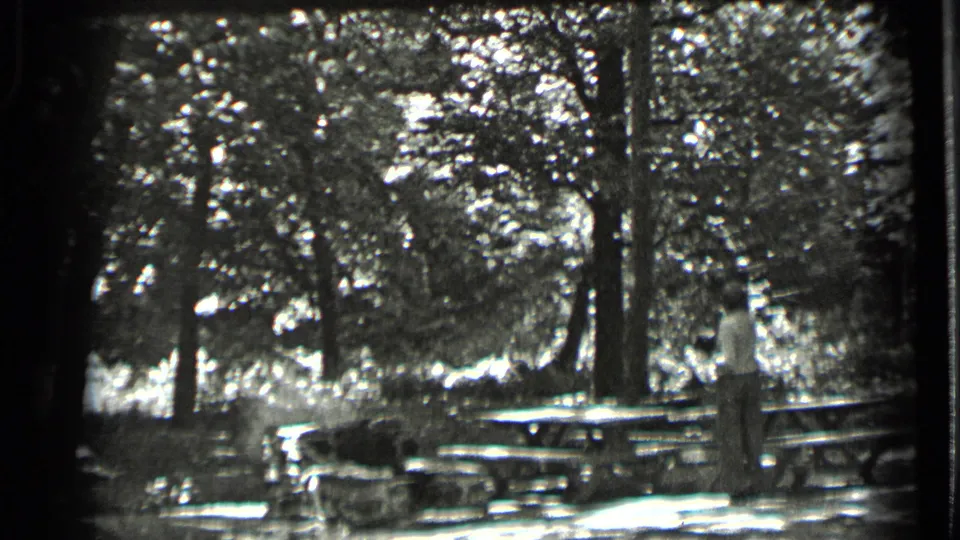 The Clear Lake picnic area appears in black-and-white 8mm footage, with a man near tables and trees in dappled light.