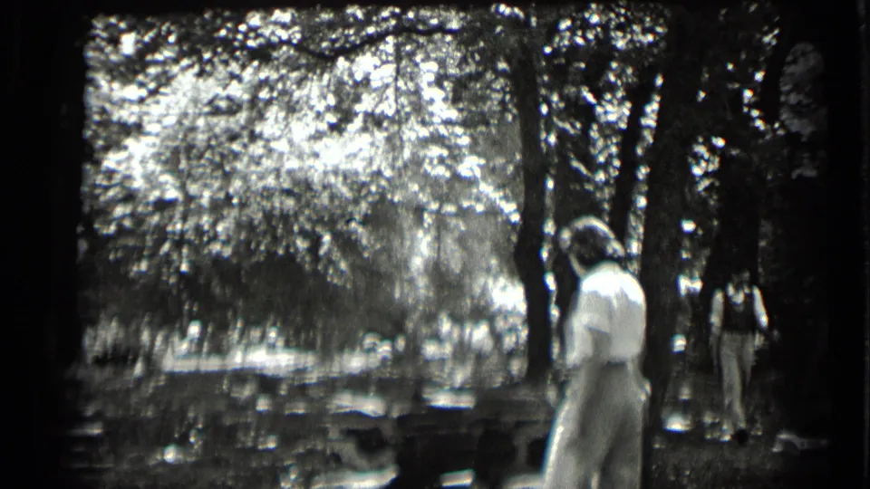 1939 Clear Lake frame showing a young woman in light clothing near trees, with water and another person partly visible behind her.