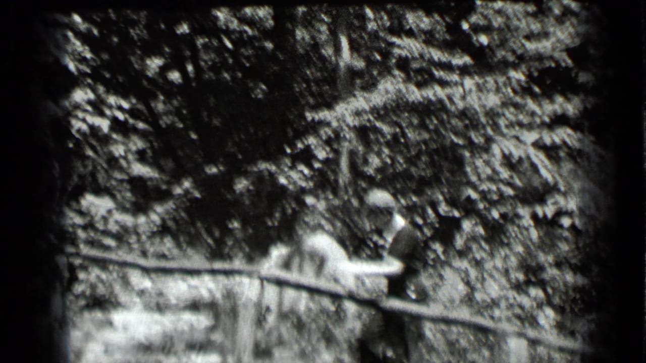 The woman continues along the wooded Clear Lake path, partly softened by motion and the black-and-white 8mm exposure.