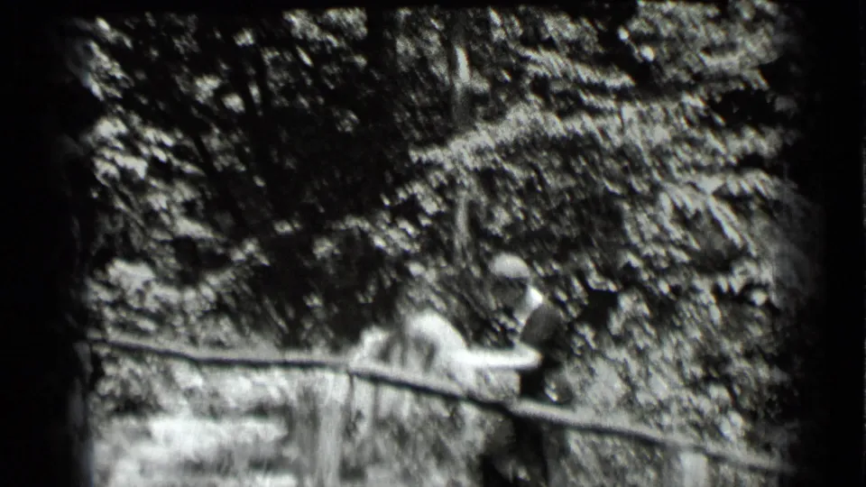 The woman continues along the wooded Clear Lake path, partly softened by motion and the black-and-white 8mm exposure.