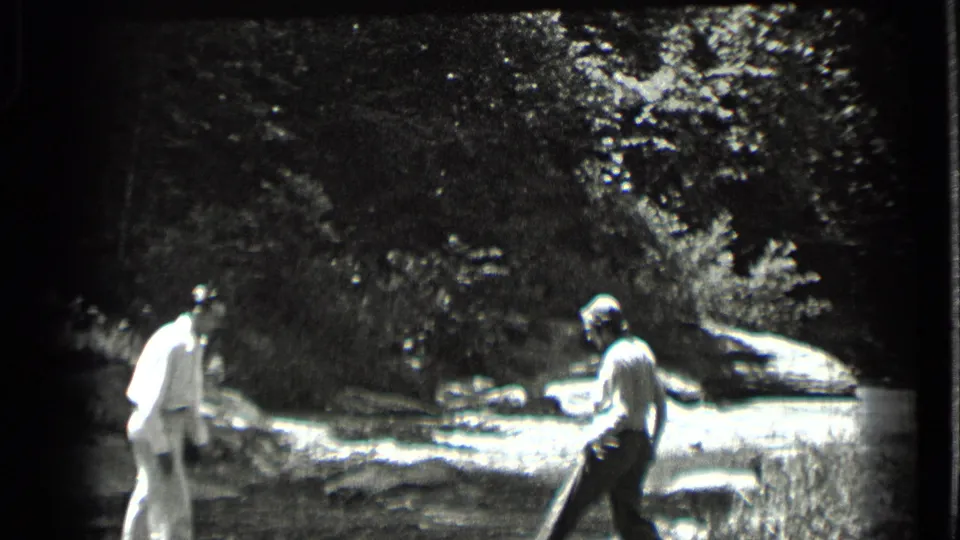 At Clear Lake, two adults appear near a shallow rocky stream, preparing to help each other across the water.