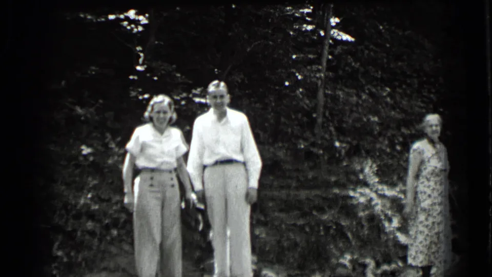 1939 Clear Lake home-movie frame showing a woman and man facing the camera as another woman stands in the wooded background.