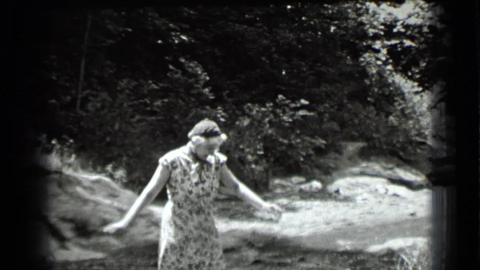 At Clear Lake, California in 1939, the woman continues across the stream with one arm extended for balance.