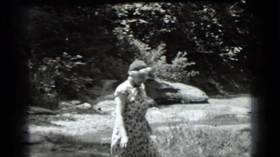 At Clear Lake, California in 1939, the woman walks near the shallow water after crossing the rocky stream edge.