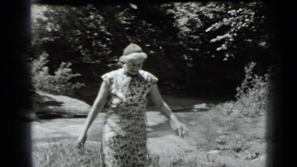 At Clear Lake, California in 1939, the woman walks toward the camera in a wooded stream setting.
