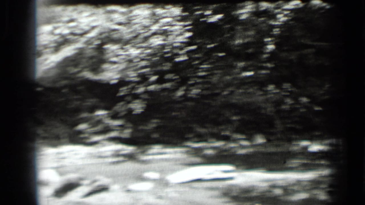 Soft, handheld view of rippled water and shoreline rocks from the Clear Lake home-movie sequence.