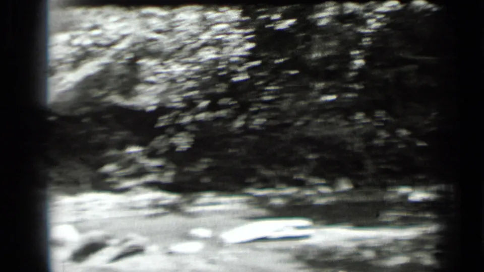 Soft, handheld view of rippled water and shoreline rocks from the Clear Lake home-movie sequence.