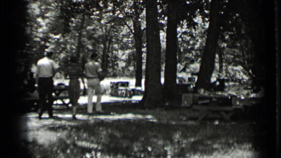 Three adults, including one in darker clothing, walk away from the camera through the Clear Lake park setting.