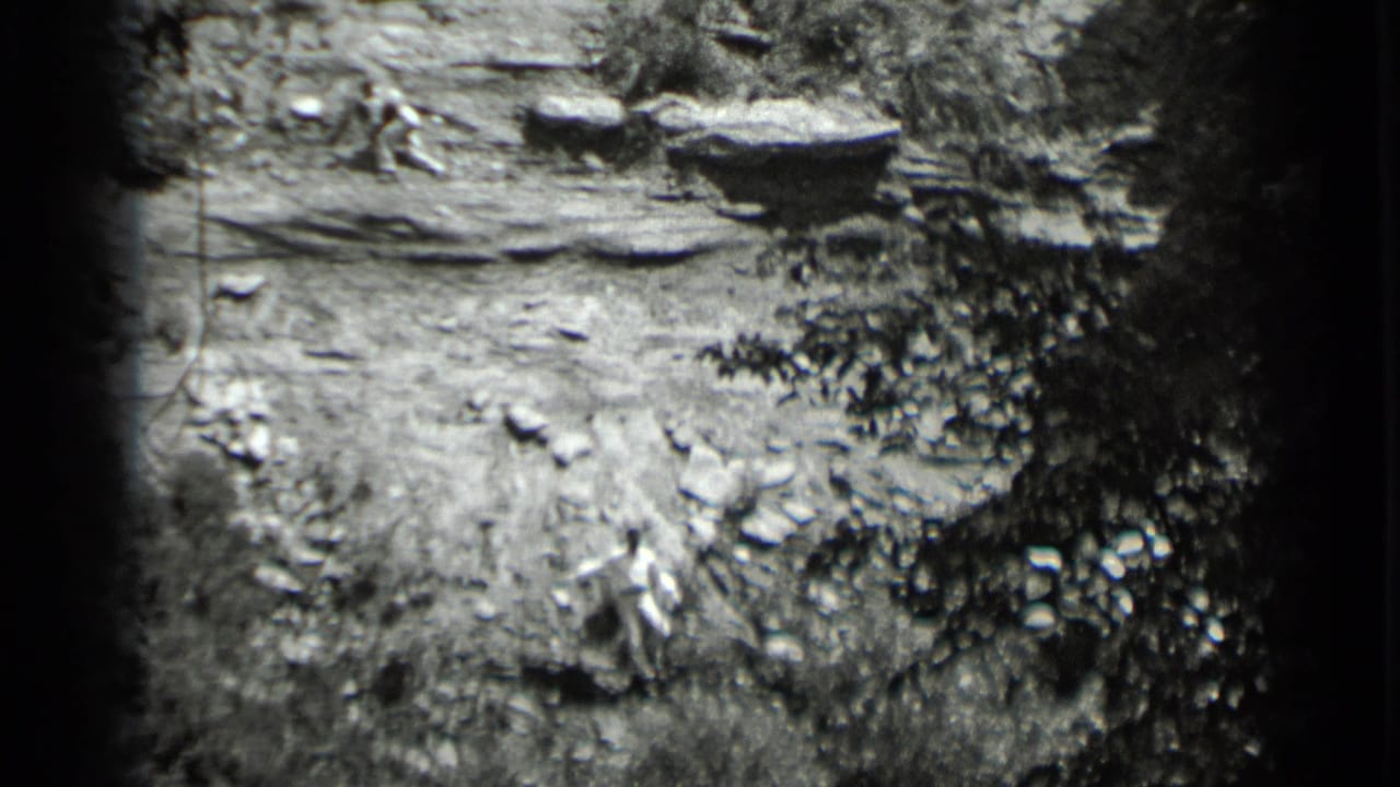 Rocky slope with brush and a partially visible person moving across uneven ground.