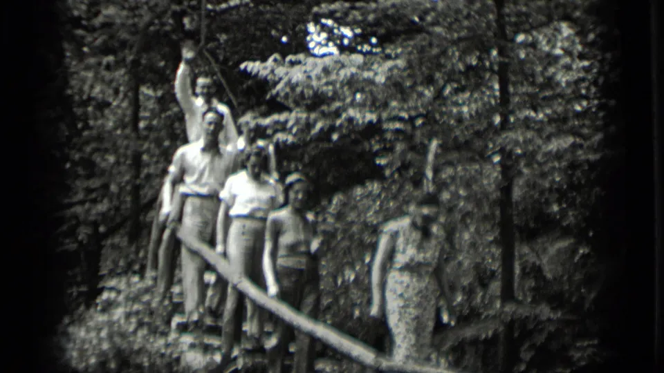 A group pauses or walks on wooden stairs in 1939 Clear Lake footage, with one adult raising an arm toward the camera.