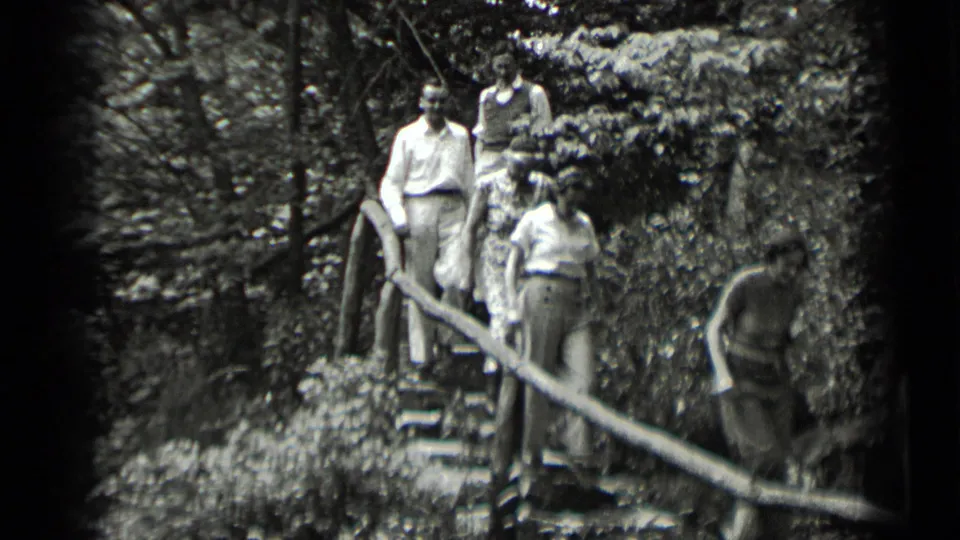 In 1939 Clear Lake, California home-movie footage, adults in period clothing walk down stone steps through dense foliage.