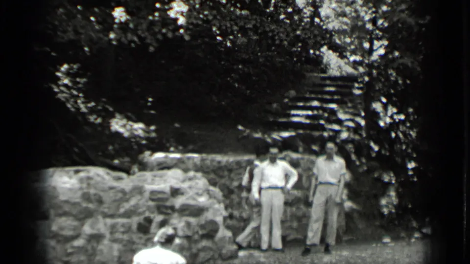 At the bottom of the Clear Lake stairway, two adults stand near a low stone wall while steps rise into the trees behind them.