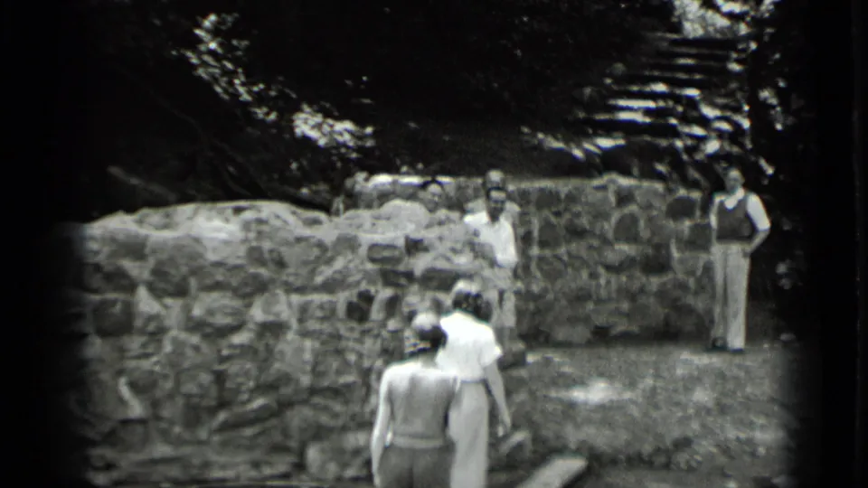 Women walk across the foreground toward men at a stone ruin in 1939 Clear Lake, California home-movie footage.
