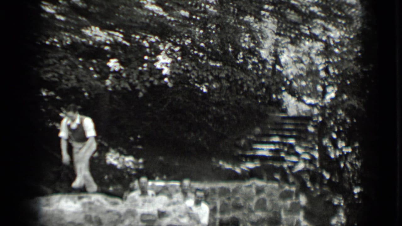 A man walks across the stone wall at Clear Lake while other adults sit or stand below in the wooded setting.