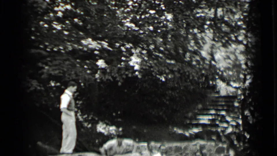At Clear Lake in 1939, a man stands on the stone wall near a seated person, framed by trees and steps.