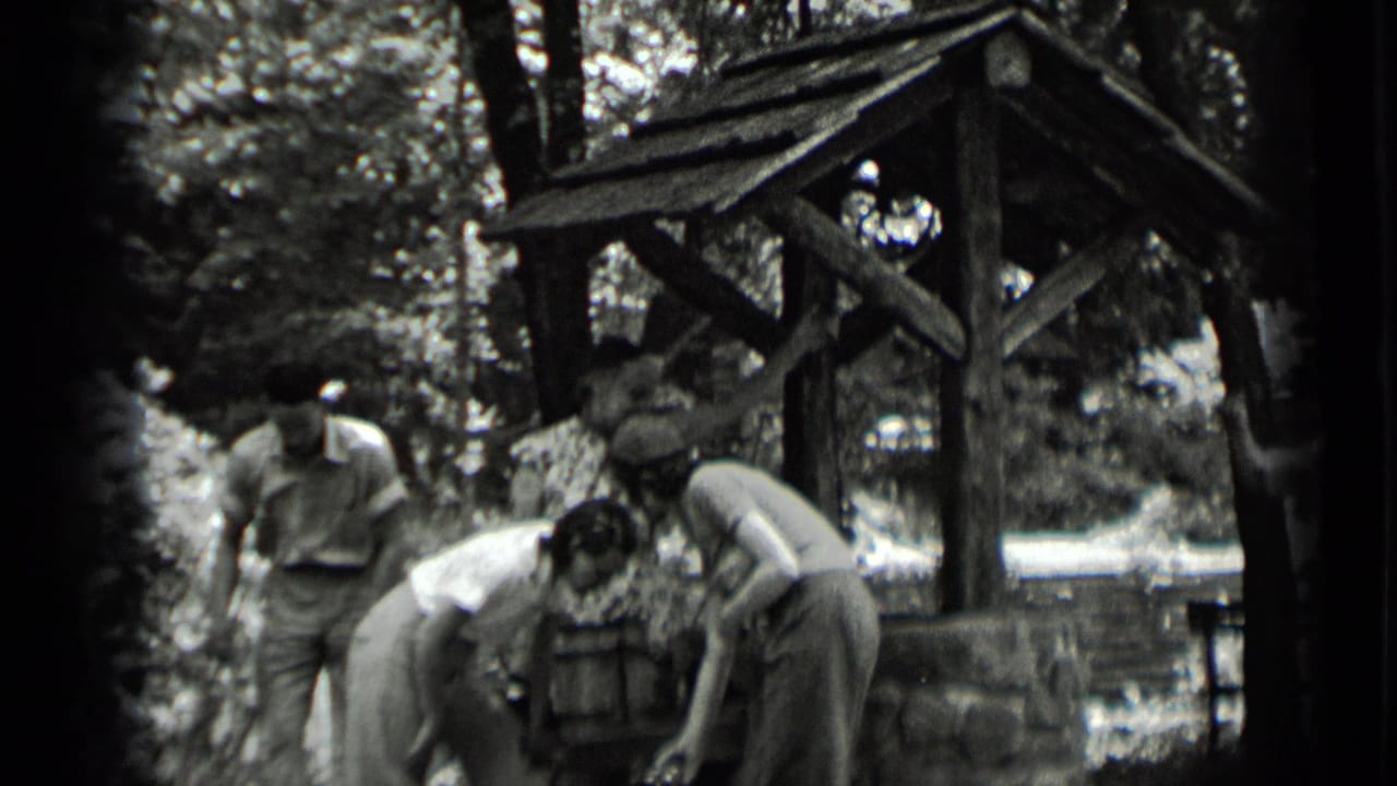 In Clear Lake, California, several young adults lean over a rustic well while one man stands to the side.