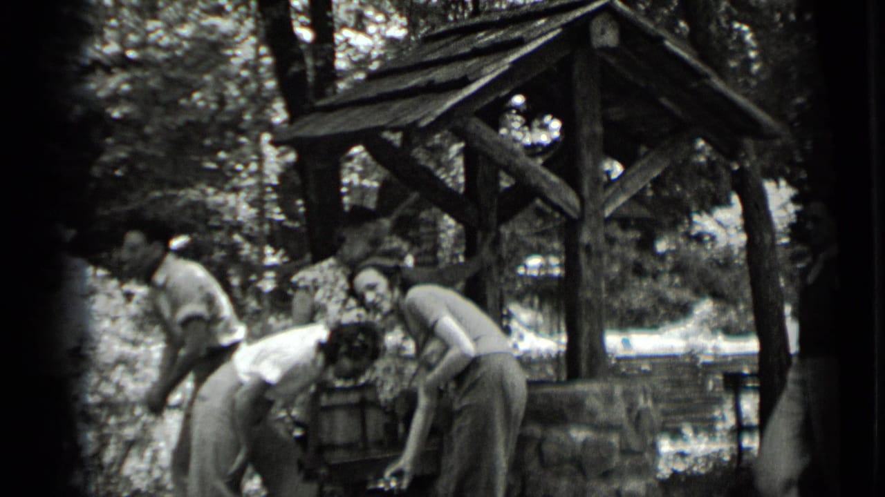 Young adults in 1939 Clear Lake footage bend close to the wooden well, partly obscured by soft 8mm exposure.