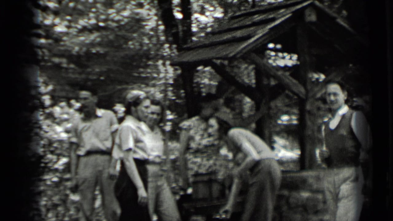 Adults in 1930s attire appear near a rustic shelter at Clear Lake, with one person bending and others facing the camera or each other.