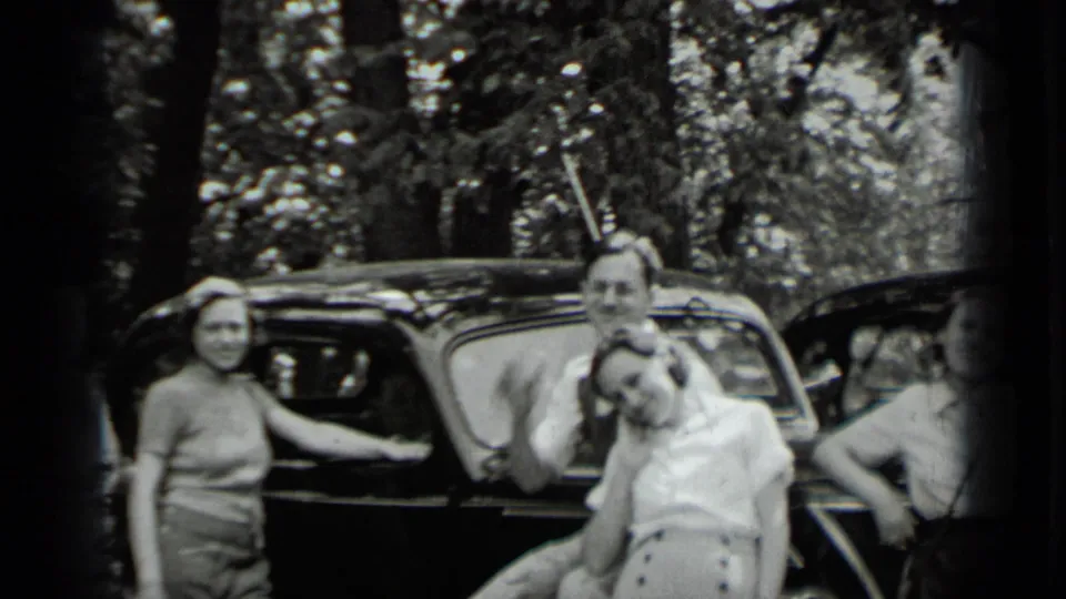 At Clear Lake in 1939, several adults gather around a black automobile, with women and men leaning or standing near the car.