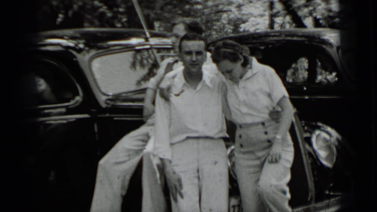 Two young adults pose beside a dark 1930s car in the Clear Lake footage, with a third person partly visible at left.
