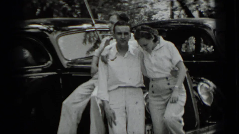 Two young adults pose beside a dark 1930s car in the Clear Lake footage, with a third person partly visible at left.