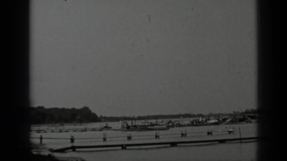 1939 8mm view of Clear Lake, California, showing moored boats along a pier beneath an overcast sky.