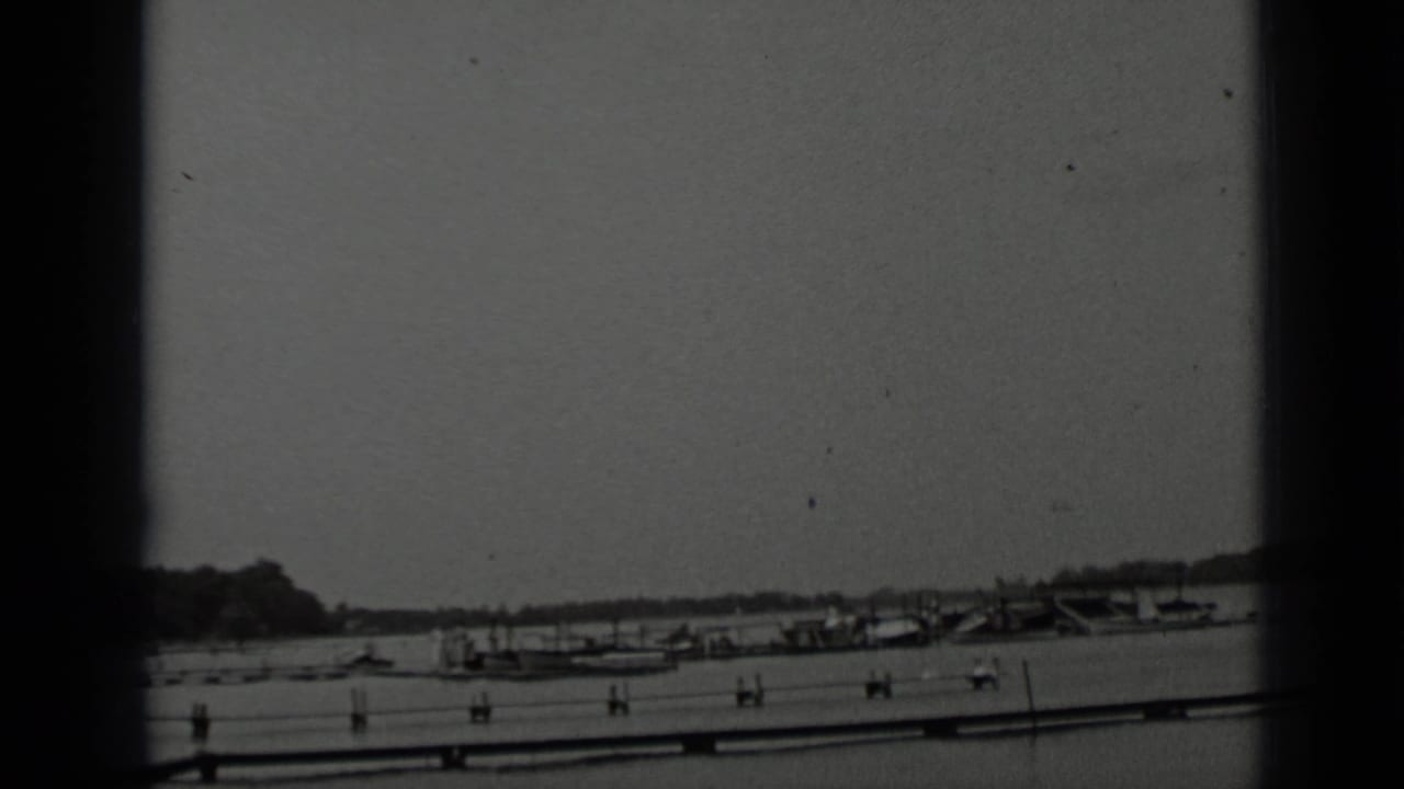 Clear Lake shoreline in 1939 home-movie footage, with boats clustered near a pier and hills in the distance.