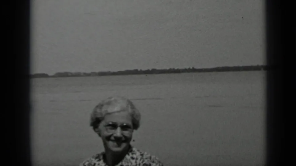 The woman remains smiling at the Clear Lake waterfront, framed low against calm water and a far shore.