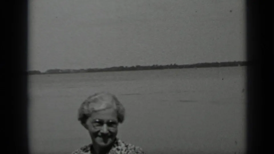 In the 1939 Clear Lake home movie, the smiling woman is partly low in the frame with lake water behind her.