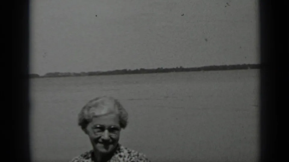 A final frame shows the older woman smiling at the Clear Lake waterfront, with soft 8mm grain and dark frame edges.