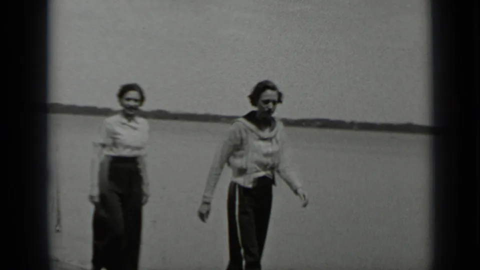 Two women walk toward the camera on a Clear Lake pier, one in a light blouse and the other in a cardigan-style top.