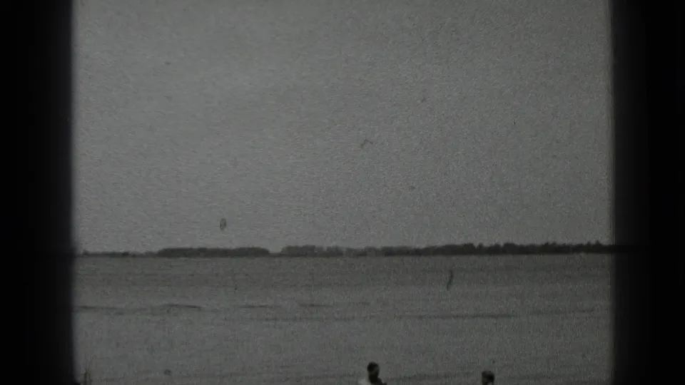 1939 Clear Lake, California home-movie frame with distant swimmers in calm water and a low shoreline beyond.