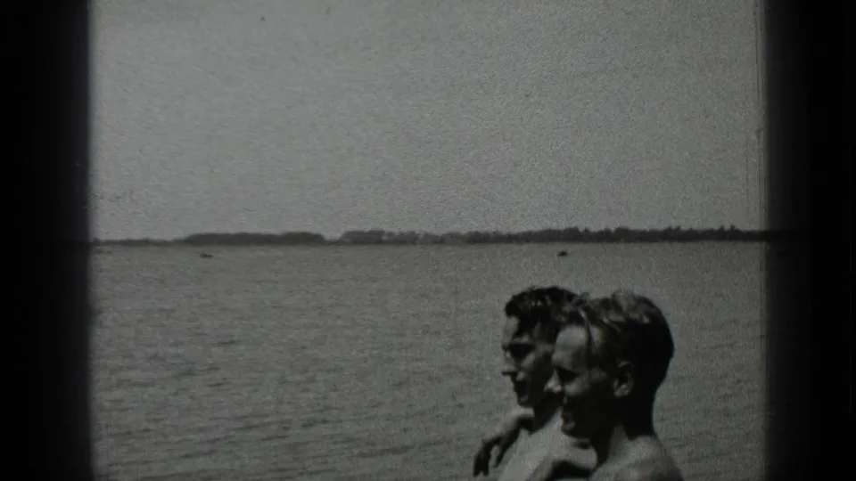 At Clear Lake, California in 1939, two adults sit close together near the shore as the lake and far shoreline fill the background.