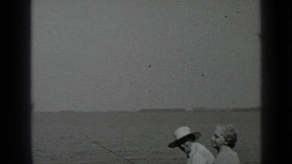 The couple remains seated beside Clear Lake, with the fishing rod angled across the water and the woman turned toward the camera.