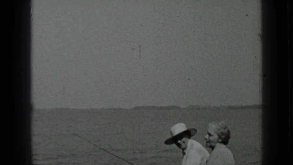 Clear Lake fishing scene with the seated couple closer to frame, the hat brim visible and the fishing line extending toward the water.