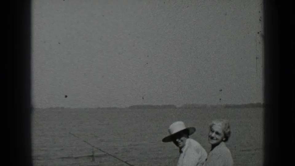 At Clear Lake, California in 1939, an older couple stands close by the water as the man wears a light wide-brimmed hat.