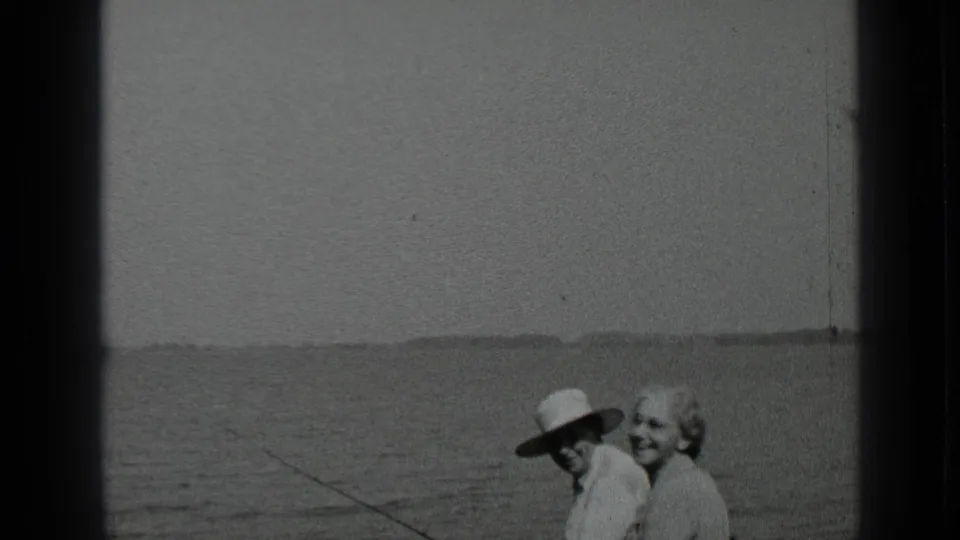 The couple remains near the Clear Lake shoreline, the man partly shaded by his hat and the woman smiling toward the camera.