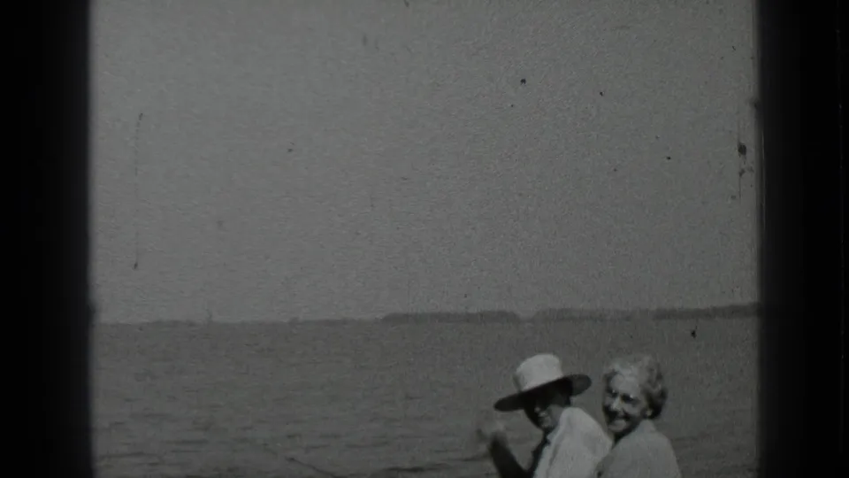 In the 1939 Clear Lake home movie, the older couple stands at the water's edge as the man lifts an arm and the woman smiles.