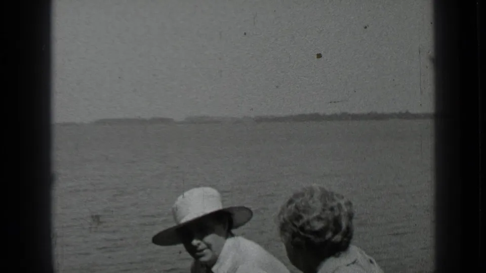 1939 Clear Lake home-movie frame showing two adults on a boat, one in a wide-brimmed white hat, with open water behind them.